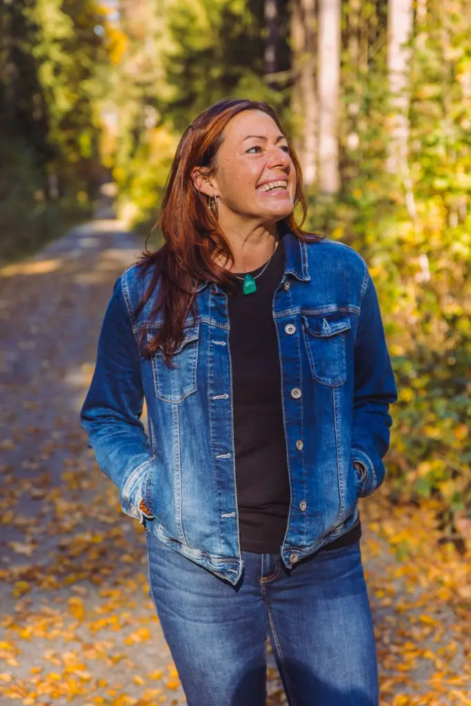 Katrin Iwicki lacht auf einem herbstlichen Waldweg